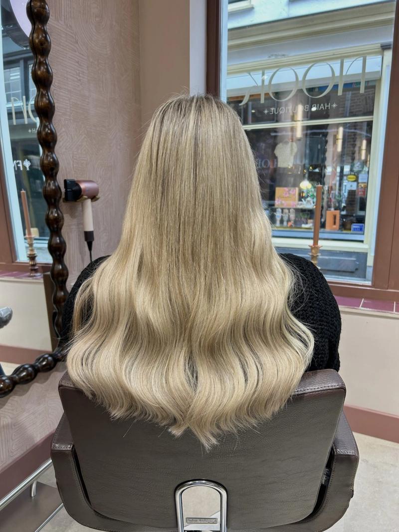 Lang blond haar met balayage, van achteren in de salonstoel