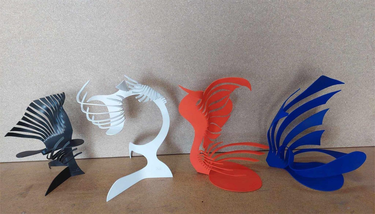 Four painted iron flame-form sculptures in black, white, red, and blue