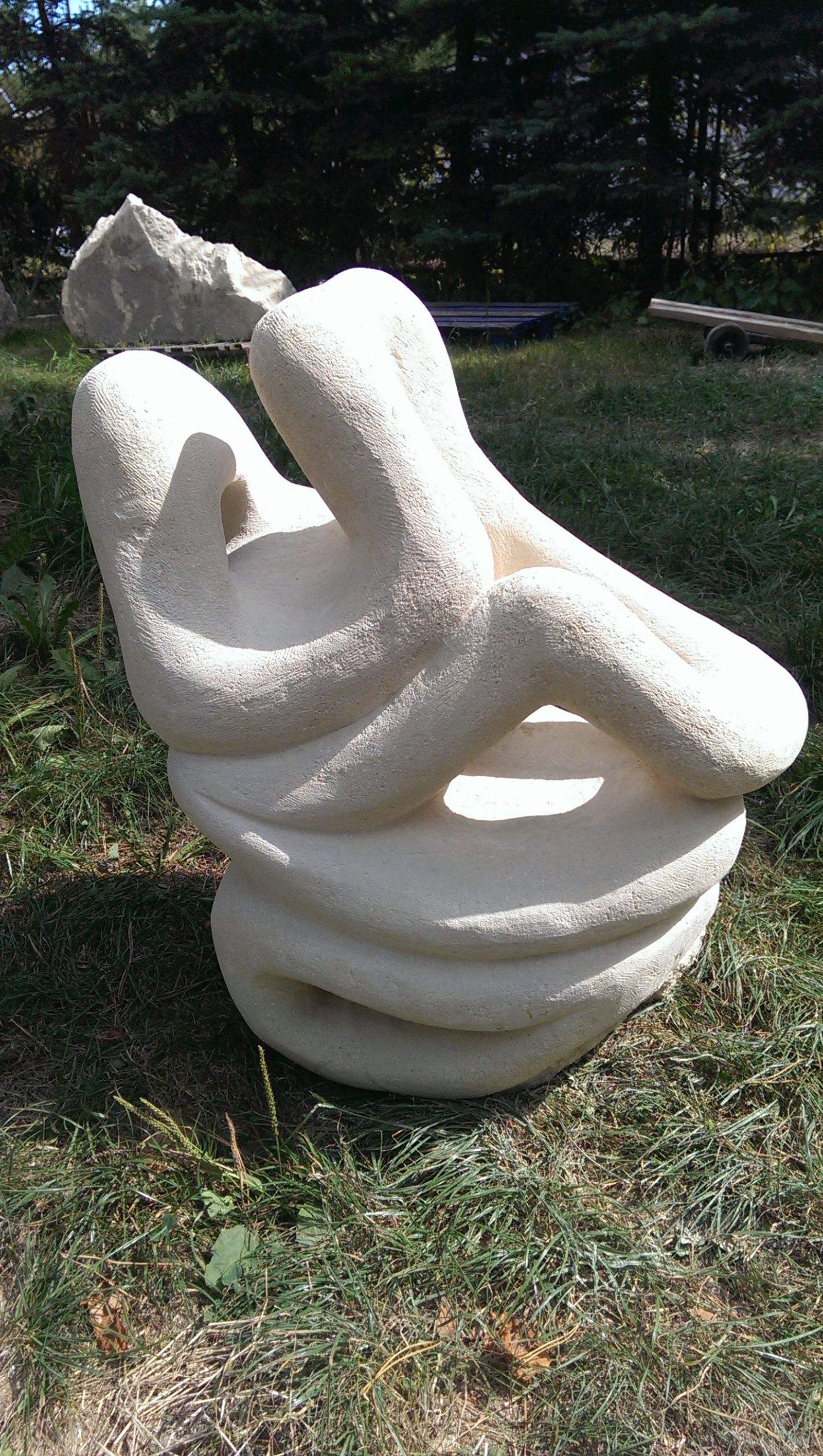 Carved stone sculpture with a circular opening, outdoors on a plinth