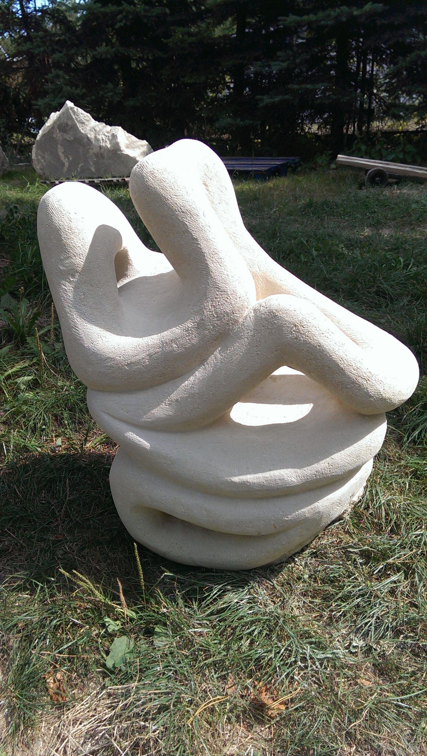 Carved stone sculpture with a circular opening, outdoors on a plinth