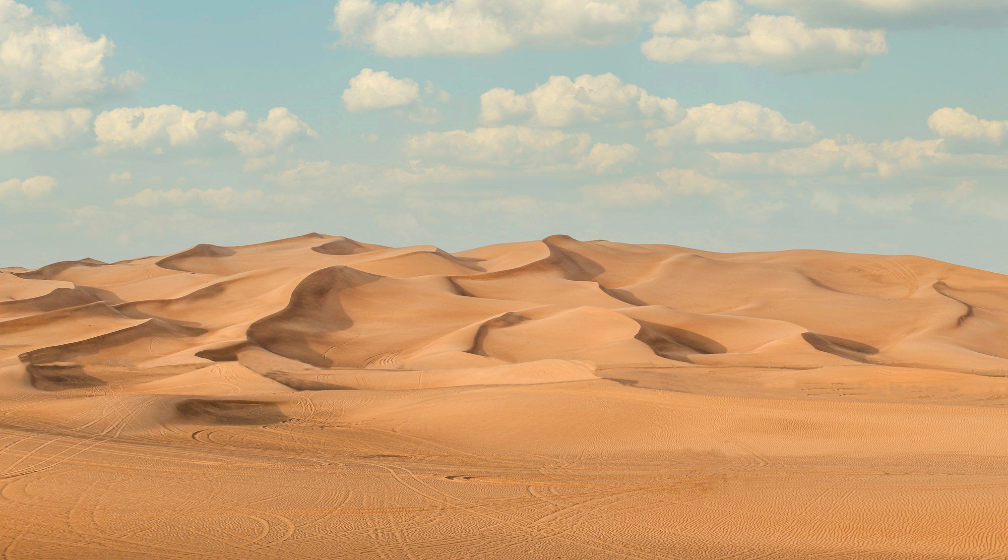Vehicles and golden sand dunes at sunset on a Dubai desert safari
