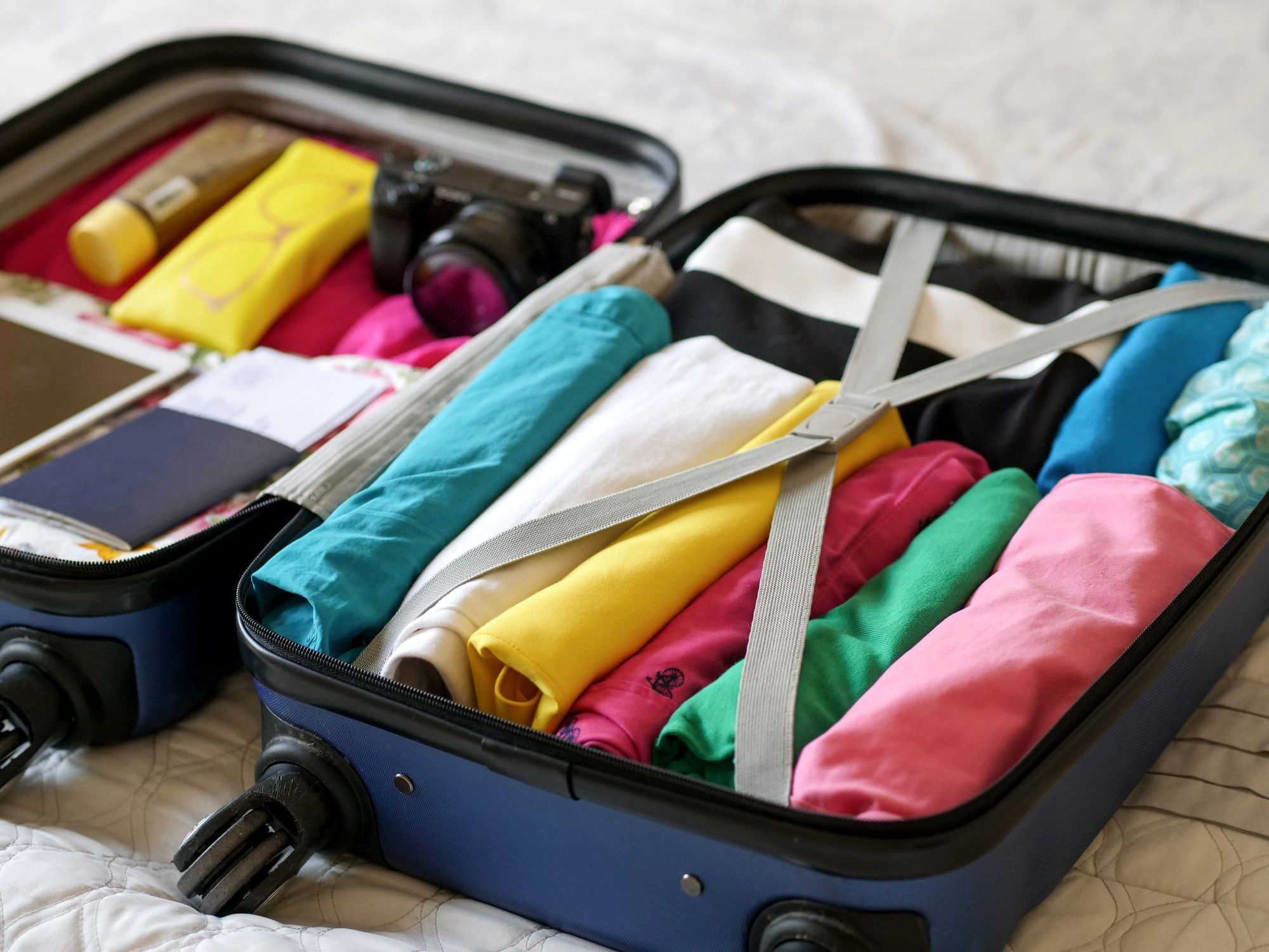 A clamshell travel backpack opened flat and packed with rolled clothes and packing cubes