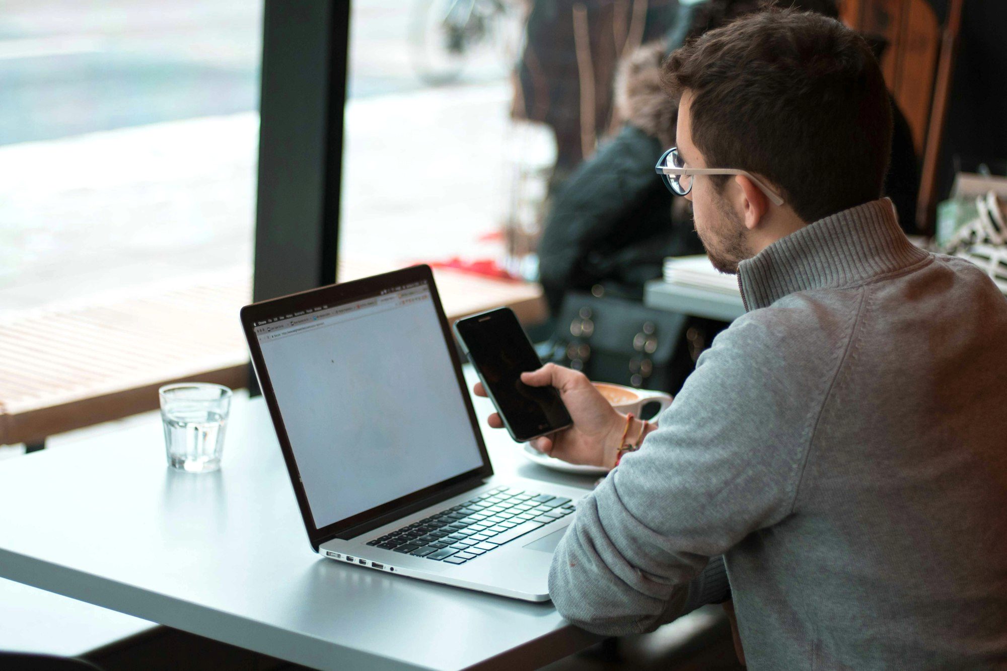 Traveler working on a phone and laptop in a cafe while abroad