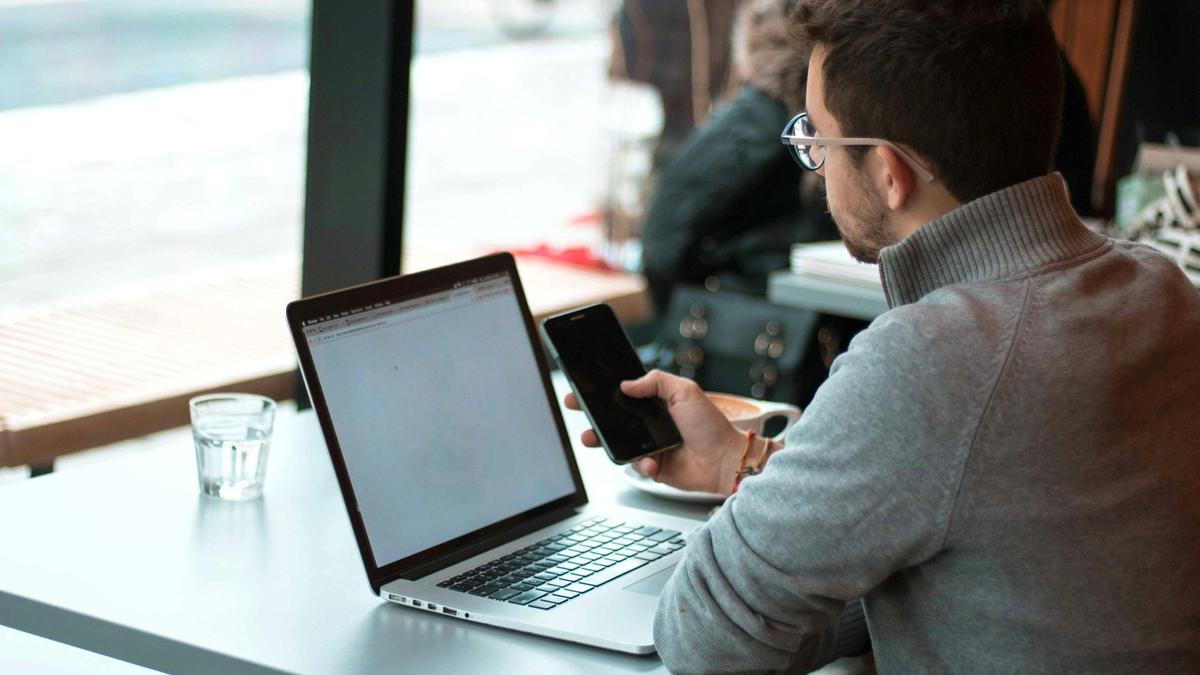 Traveler working on a phone and laptop in a cafe while abroad