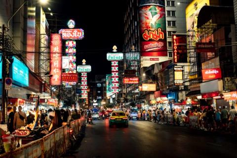 Steam and neon over crowded street food stalls on Yaowarat Road in Bangkok's Chinatown at night
