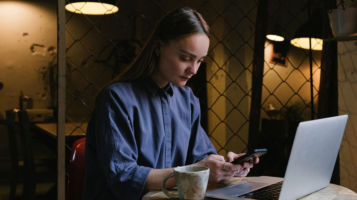 Traveler working on a phone and laptop in a cafe while abroad