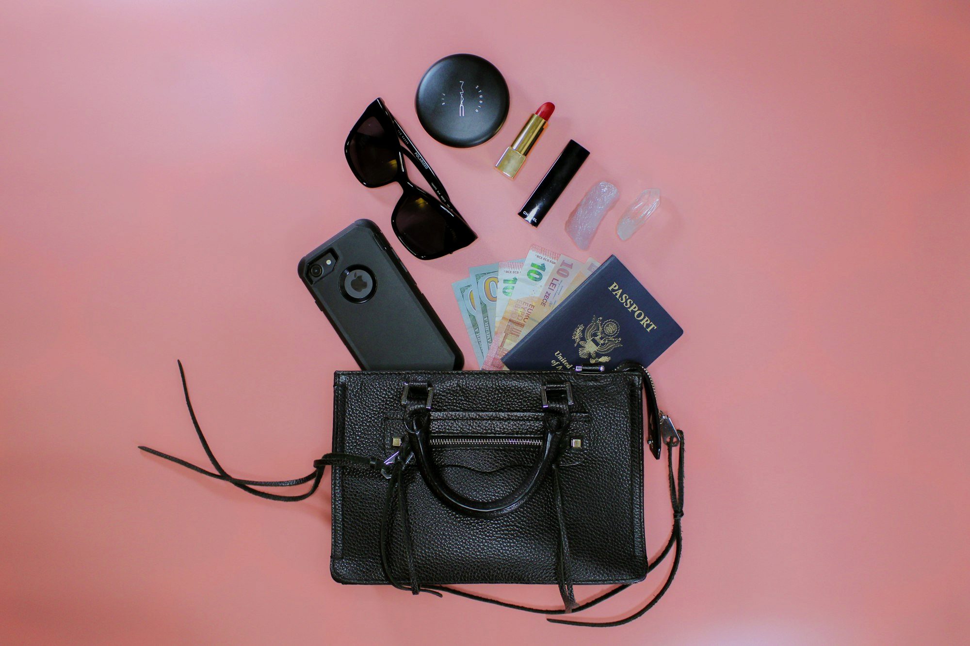 Flat lay of a minimalist capsule travel wardrobe with merino shirts, socks, and a rain shell