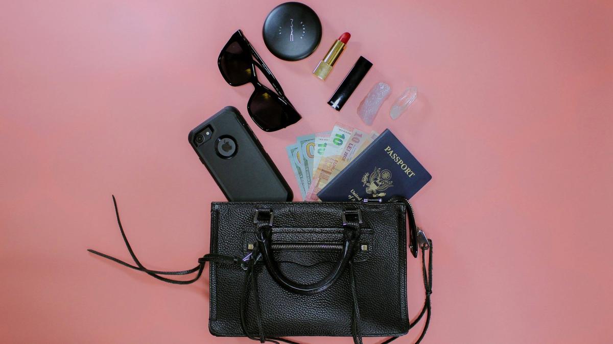 Flat lay of a minimalist capsule travel wardrobe with merino shirts, socks, and a rain shell