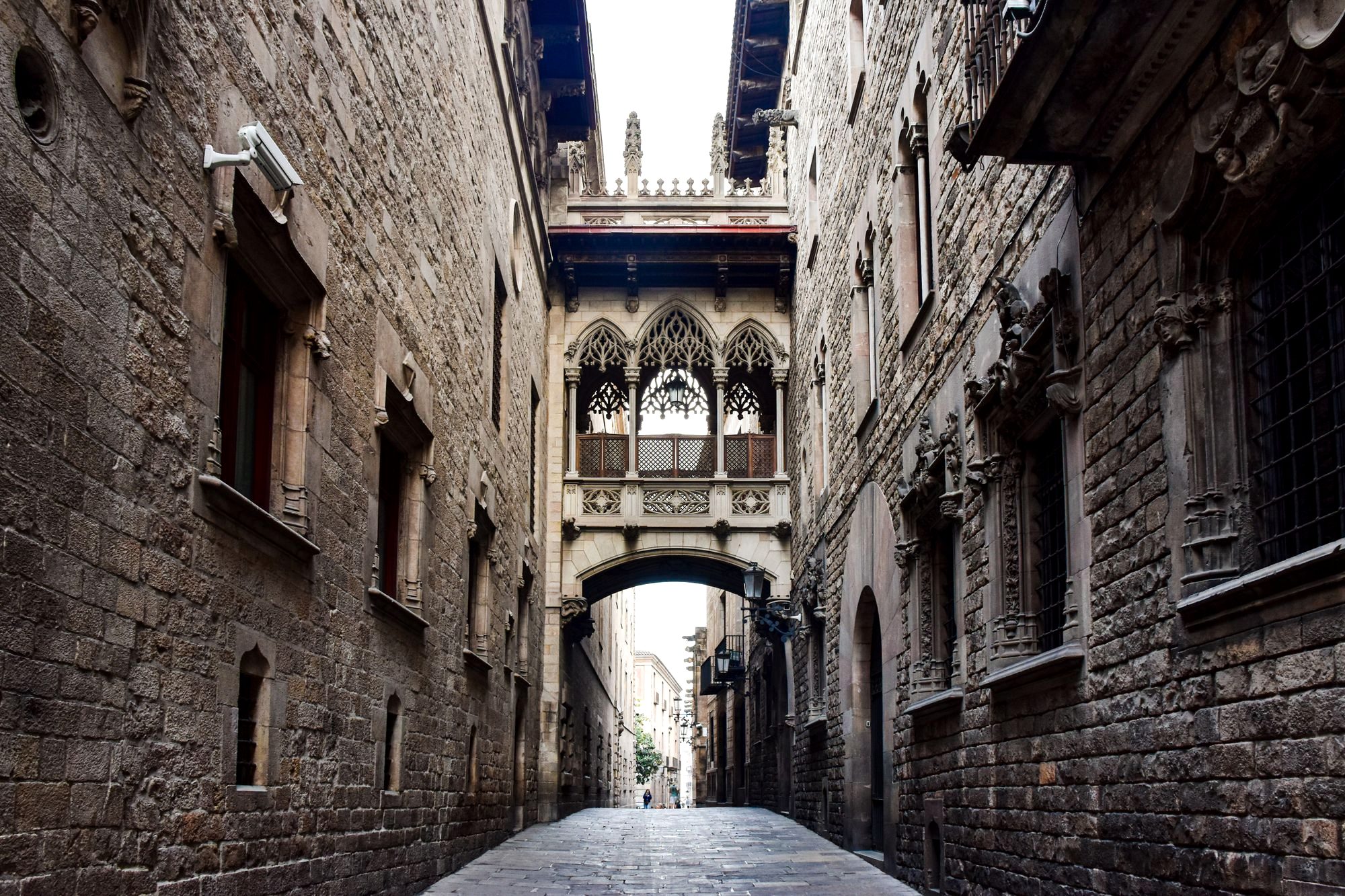 A narrow medieval stone alley in Barcelona's Gothic Quarter with iron balconies