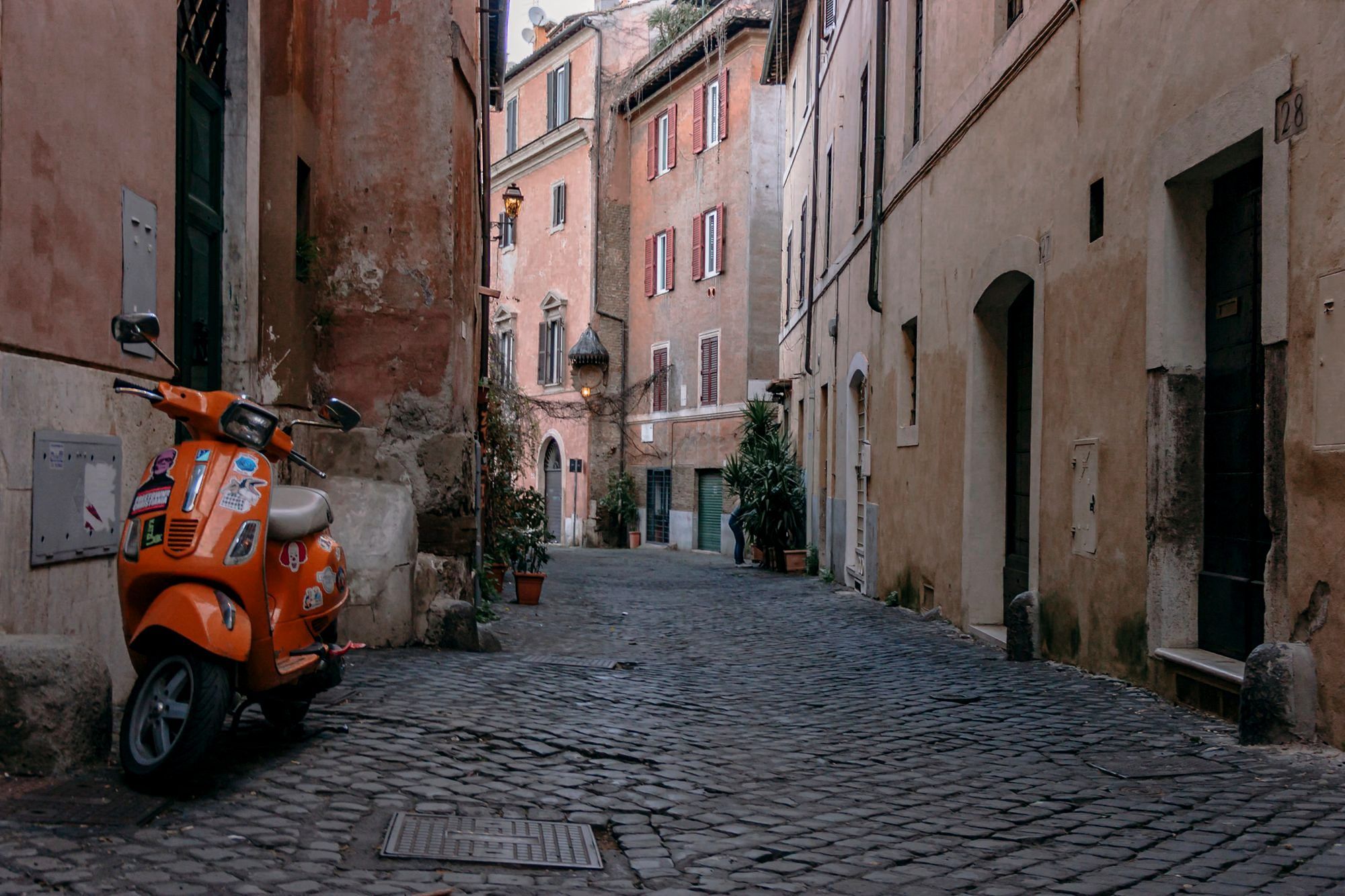 A narrow ochre-walled cobbled lane strung with ivy in Rome's Trastevere
