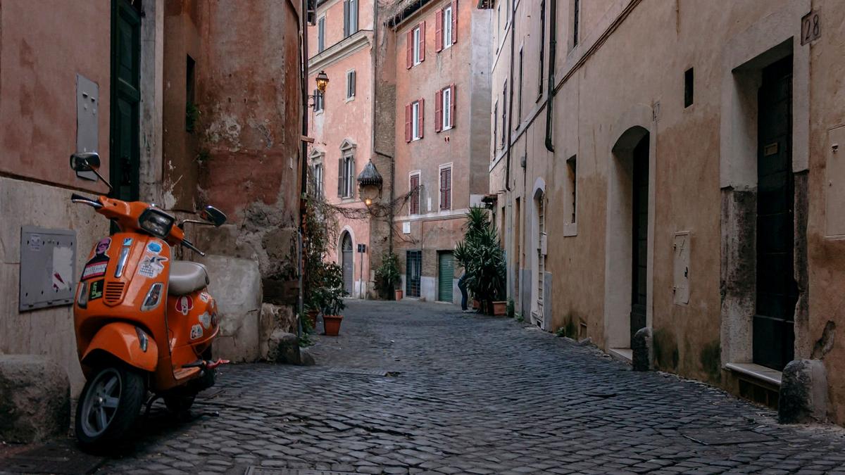 A narrow ochre-walled cobbled lane strung with ivy in Rome's Trastevere