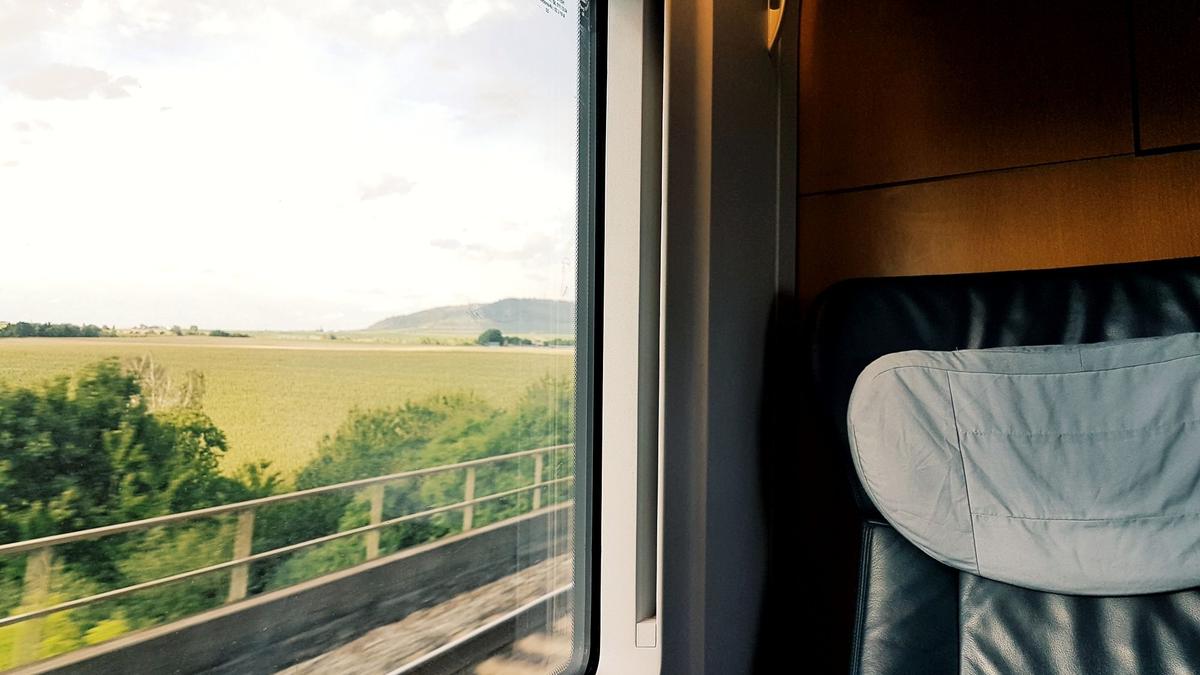 A regional train winding through green countryside seen from the window