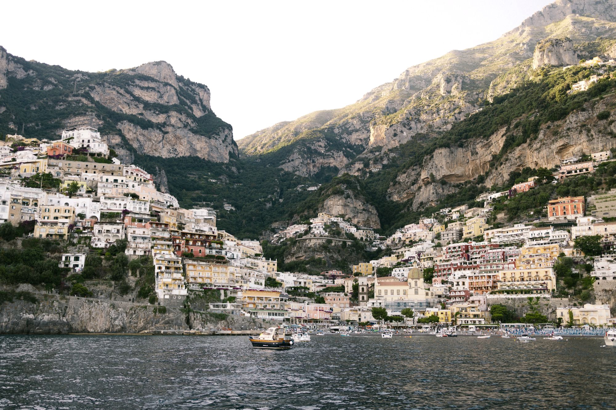 A small boat on calm water at sunset below the cliffs near Positano