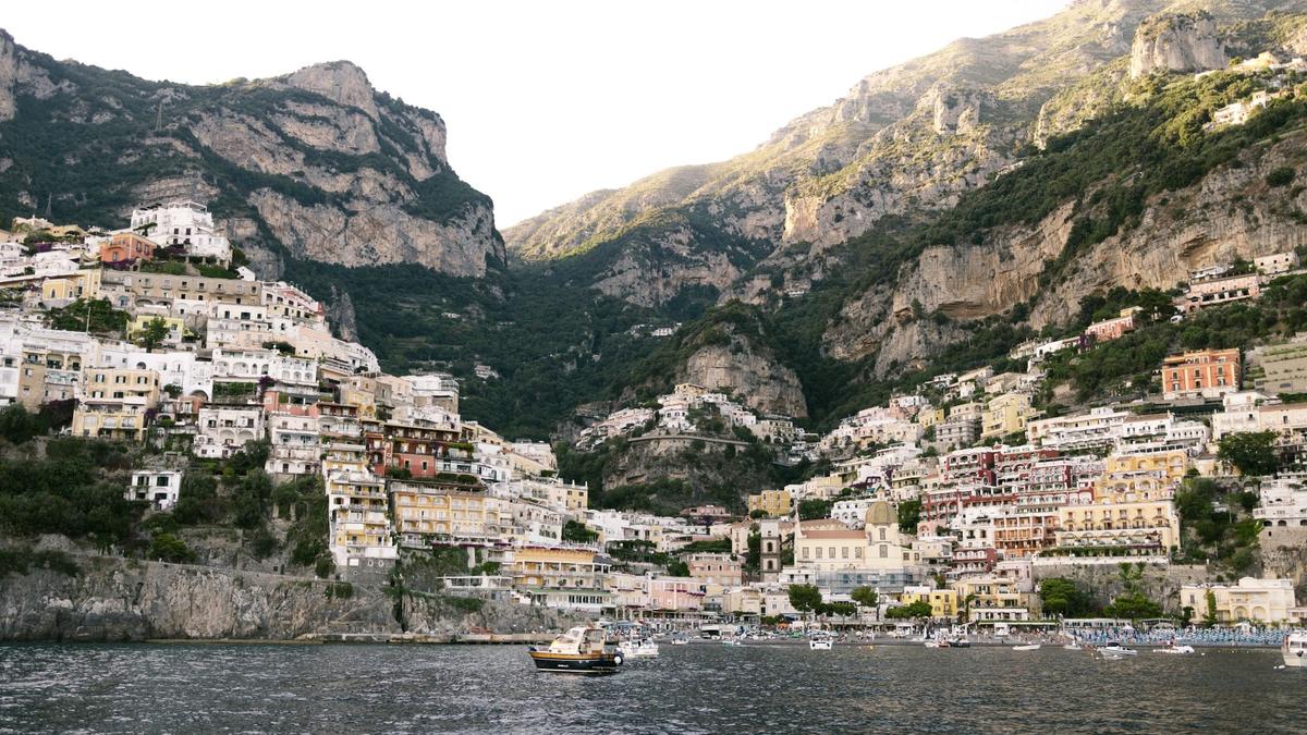 A small boat on calm water at sunset below the cliffs near Positano