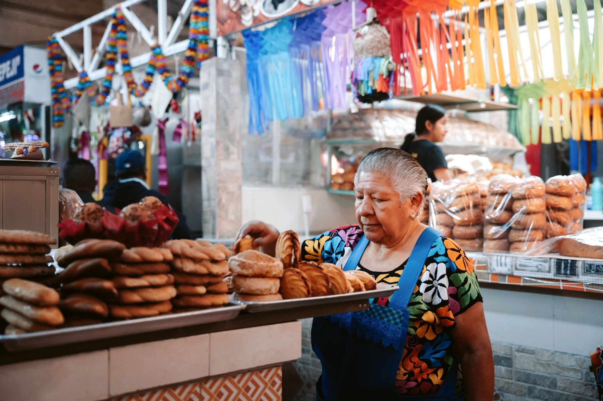 A giant crisp tlayuda topped with beans, quesillo, and grilled meat at a Oaxaca market stall