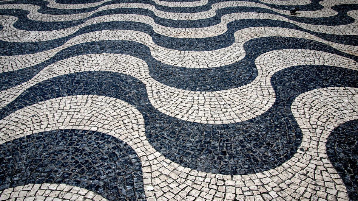 Lisbon's calçada portuguesa mosaic pavement in a wave pattern underfoot