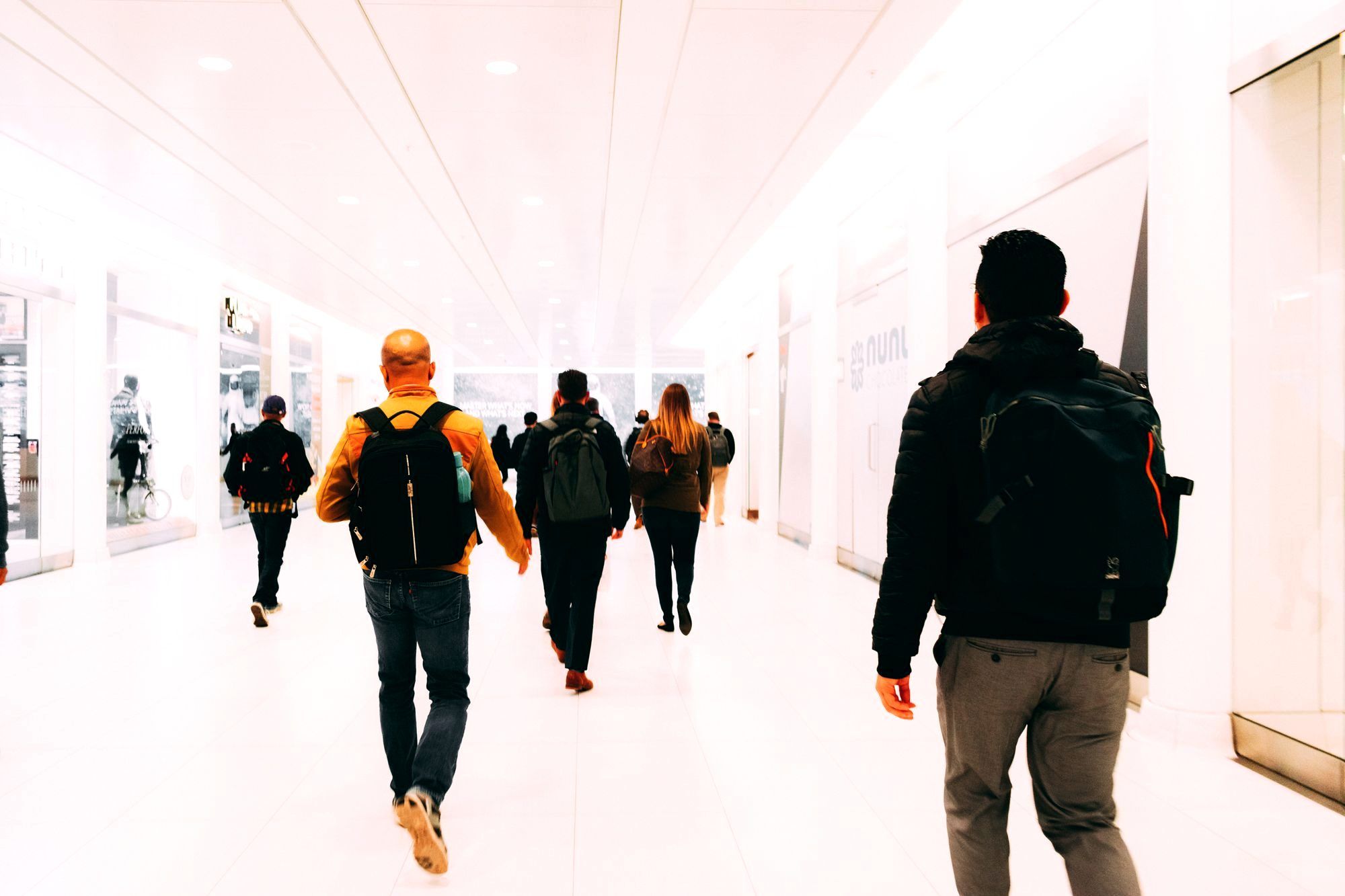 A backpacker walking through an airport terminal carrying a single carry-on backpack
