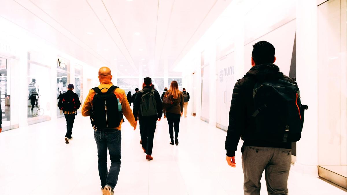 A backpacker walking through an airport terminal carrying a single carry-on backpack