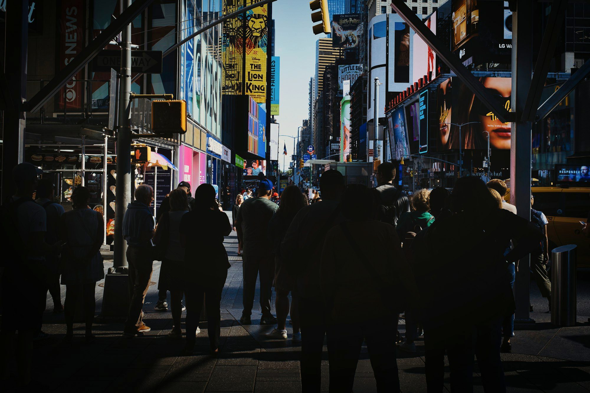 Crowds crossing a busy Manhattan avenue in New York City