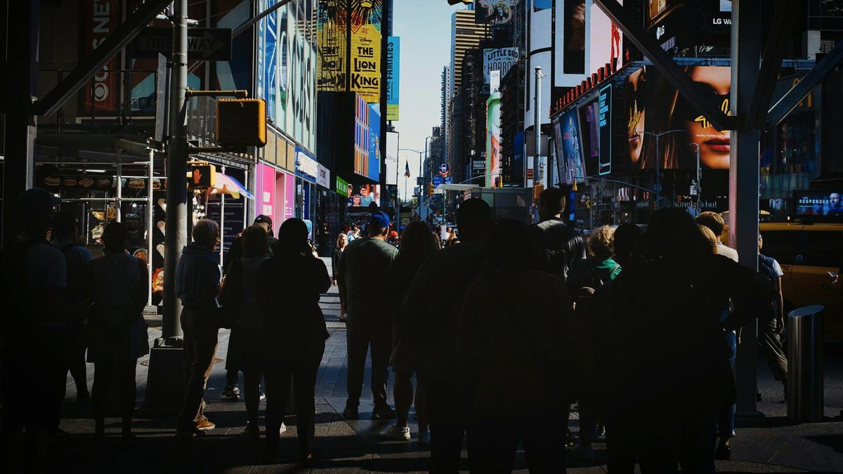 Crowds crossing a busy Manhattan avenue in New York City