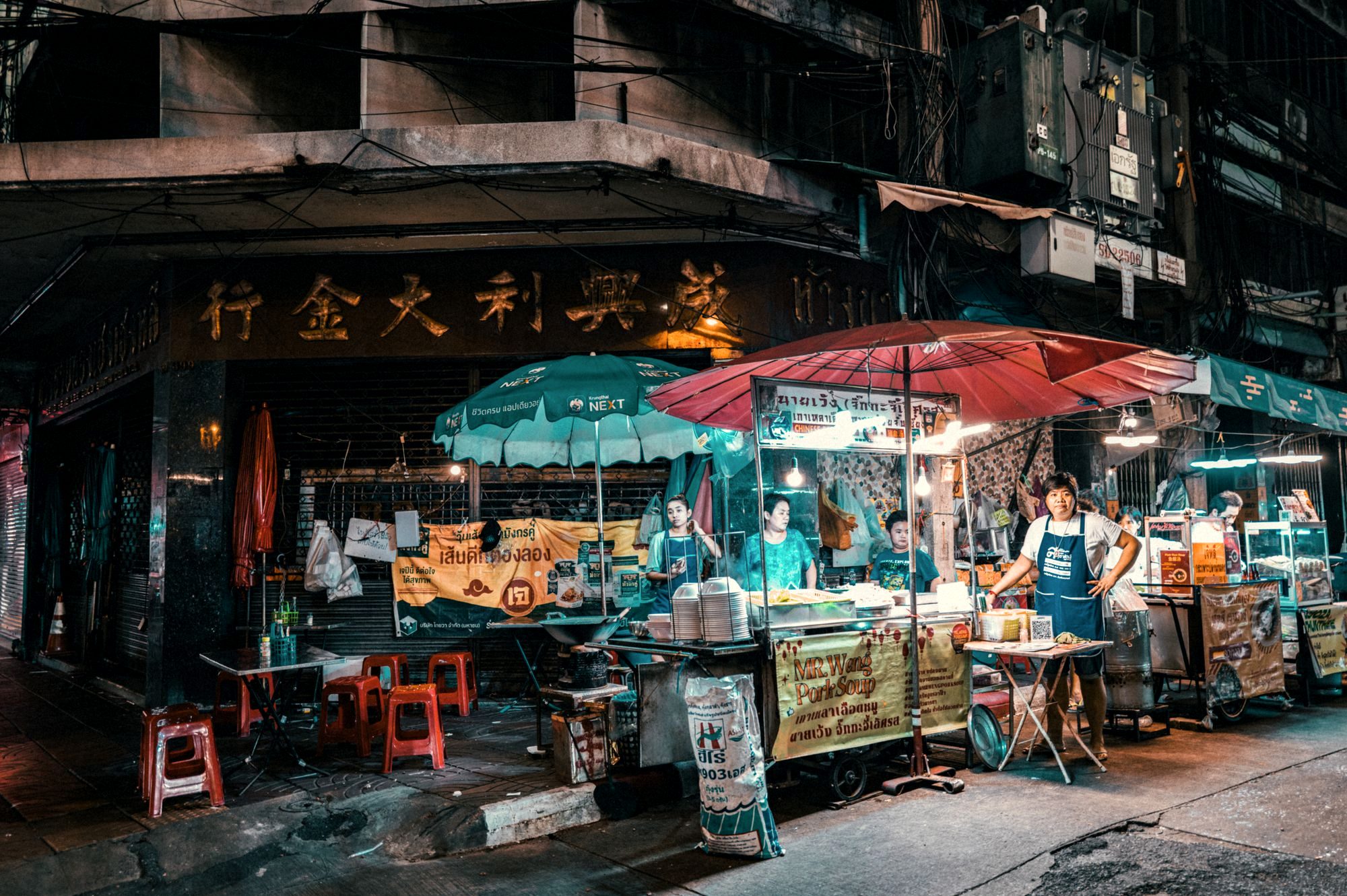 Steam and neon over a crowded row of street food woks on Yaowarat Road, Bangkok Chinatown at night