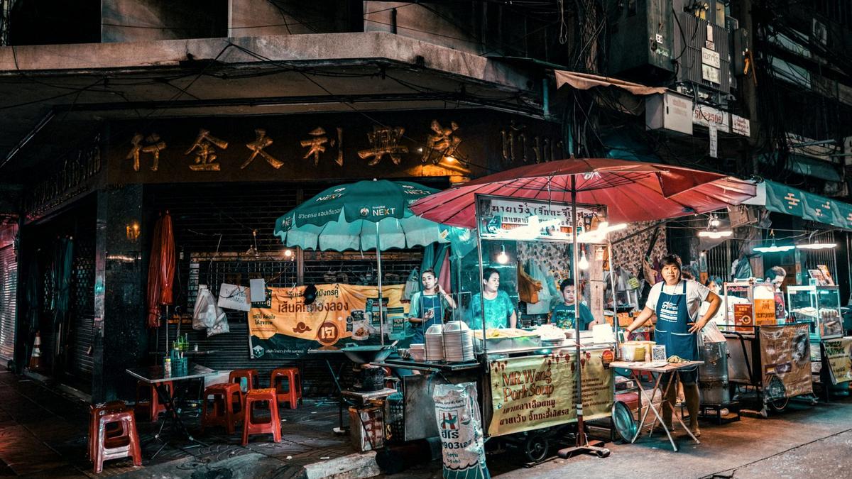 Steam and neon over a crowded row of street food woks on Yaowarat Road, Bangkok Chinatown at night