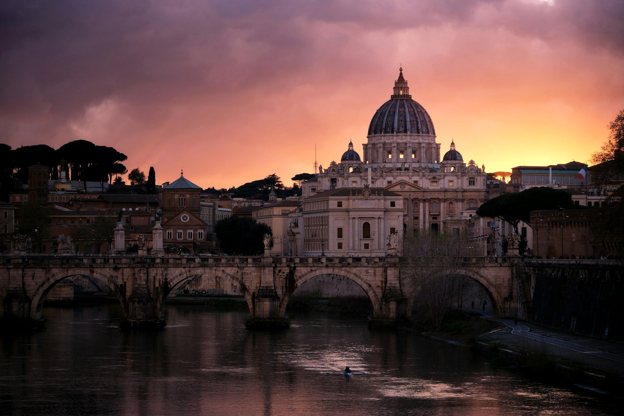 St. Peter's Basilica dome glowing at sunset above the Tiber River near Rome's Prati district