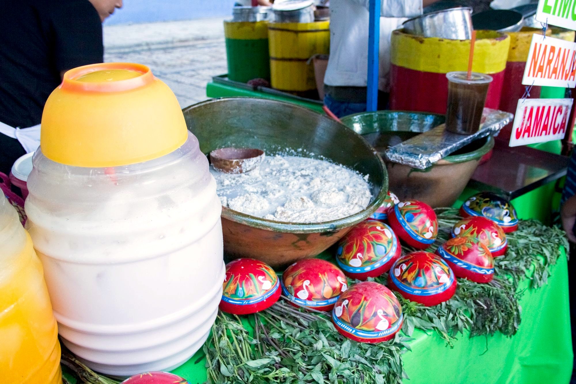 A charcoal-grilled tlayuda being prepared at a busy Oaxaca market stall