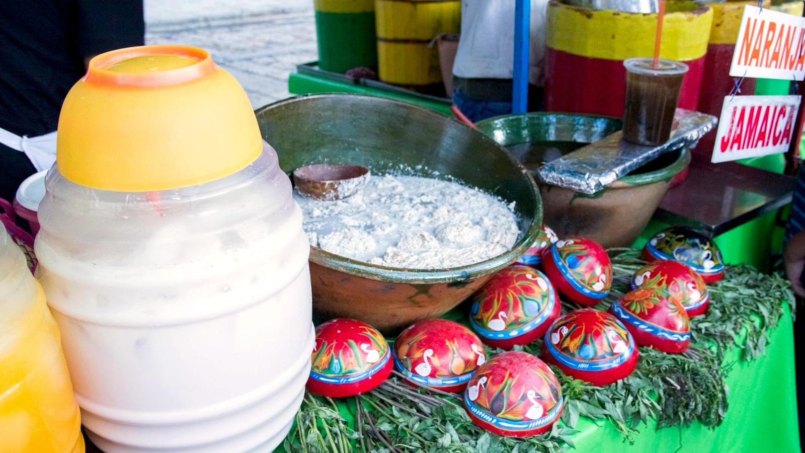 A charcoal-grilled tlayuda being prepared at a busy Oaxaca market stall