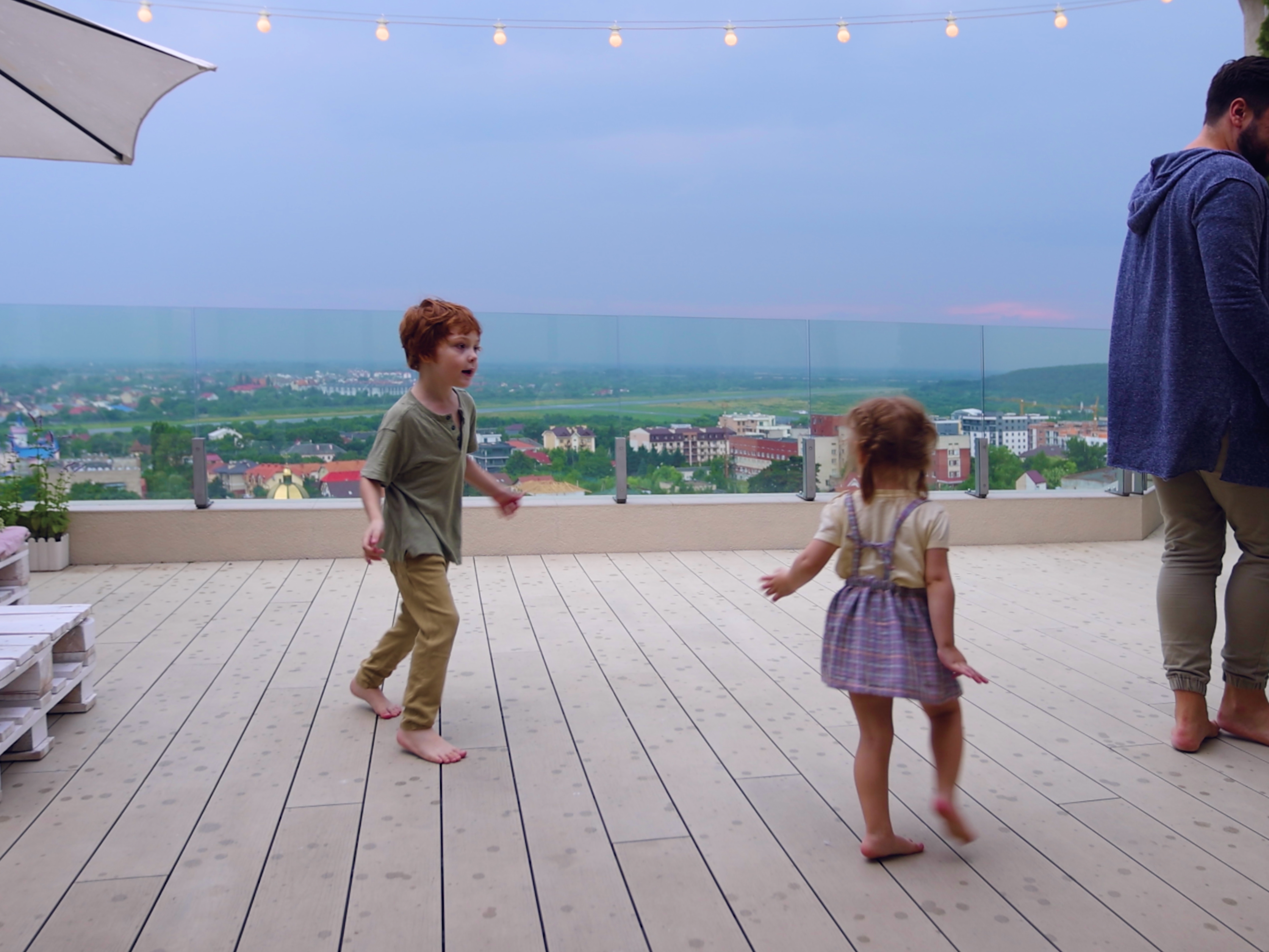Children playing on a sunlit deck overlooking a scenic valley, showcasing outdoor living spaces built with wood products