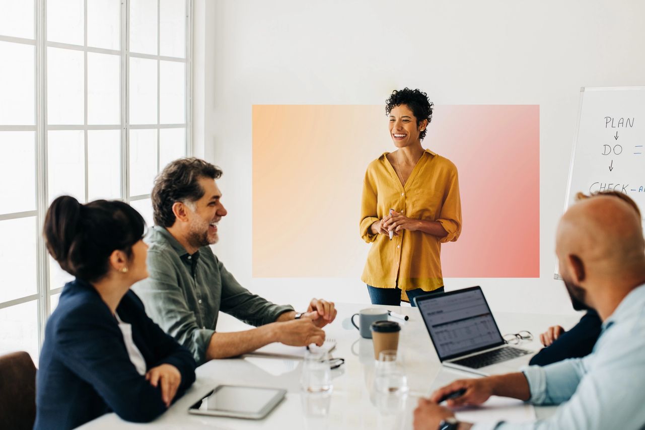 Smiling woman leading a marketing strategy meeting with colleagues around a conference table