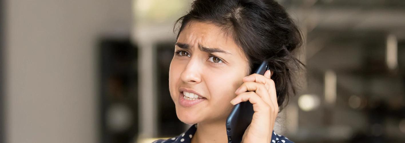 Frustrated woman grimacing while talking on a phone