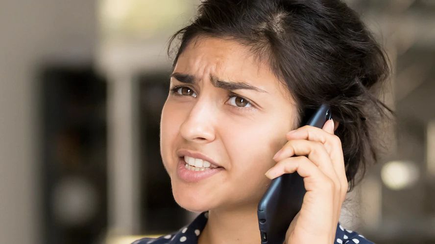 Frustrated woman grimacing while talking on a phone