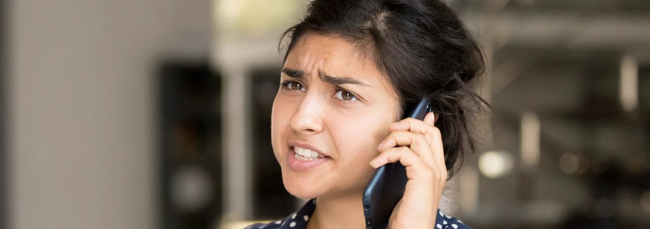 Frustrated woman grimacing while talking on a phone