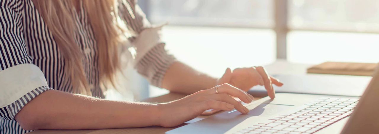 Woman typing on a keyboard at a sunlit desk