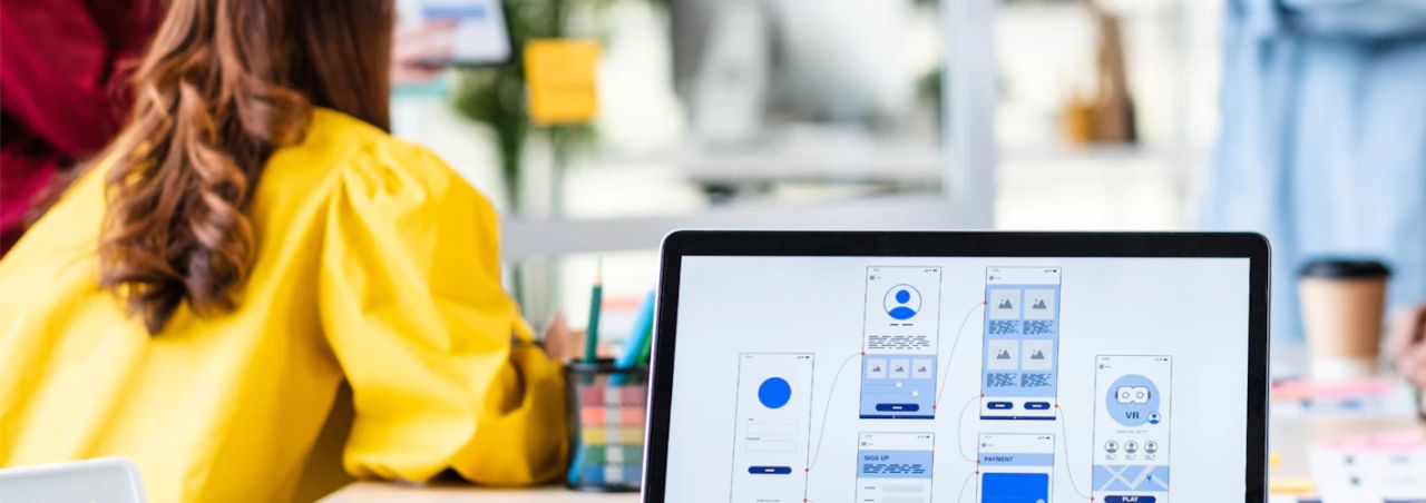 Designer reviewing mobile app wireframes on a laptop screen