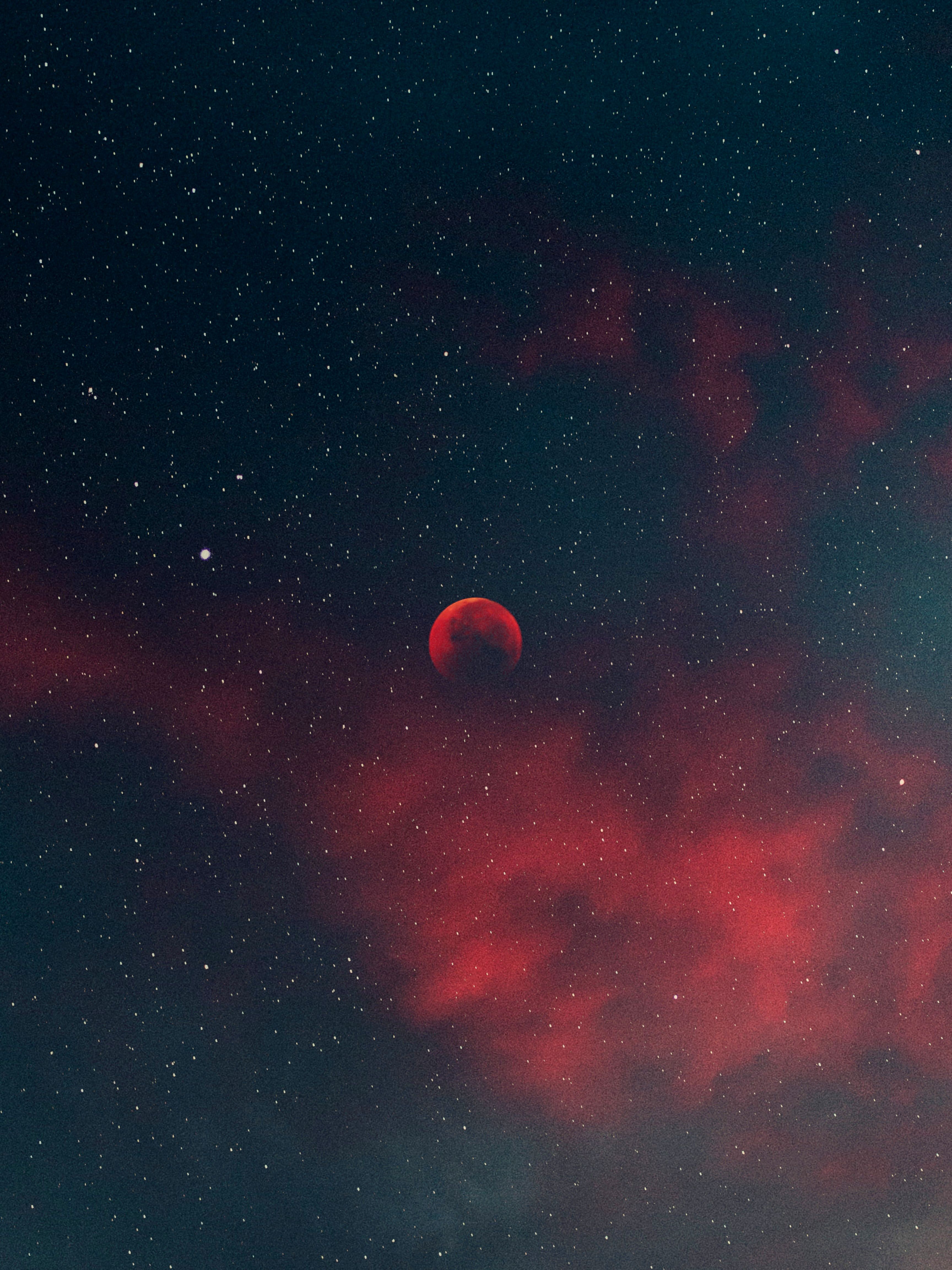 Blood moon glowing red against a deep starfield with crimson nebula clouds, representing space science and exploration