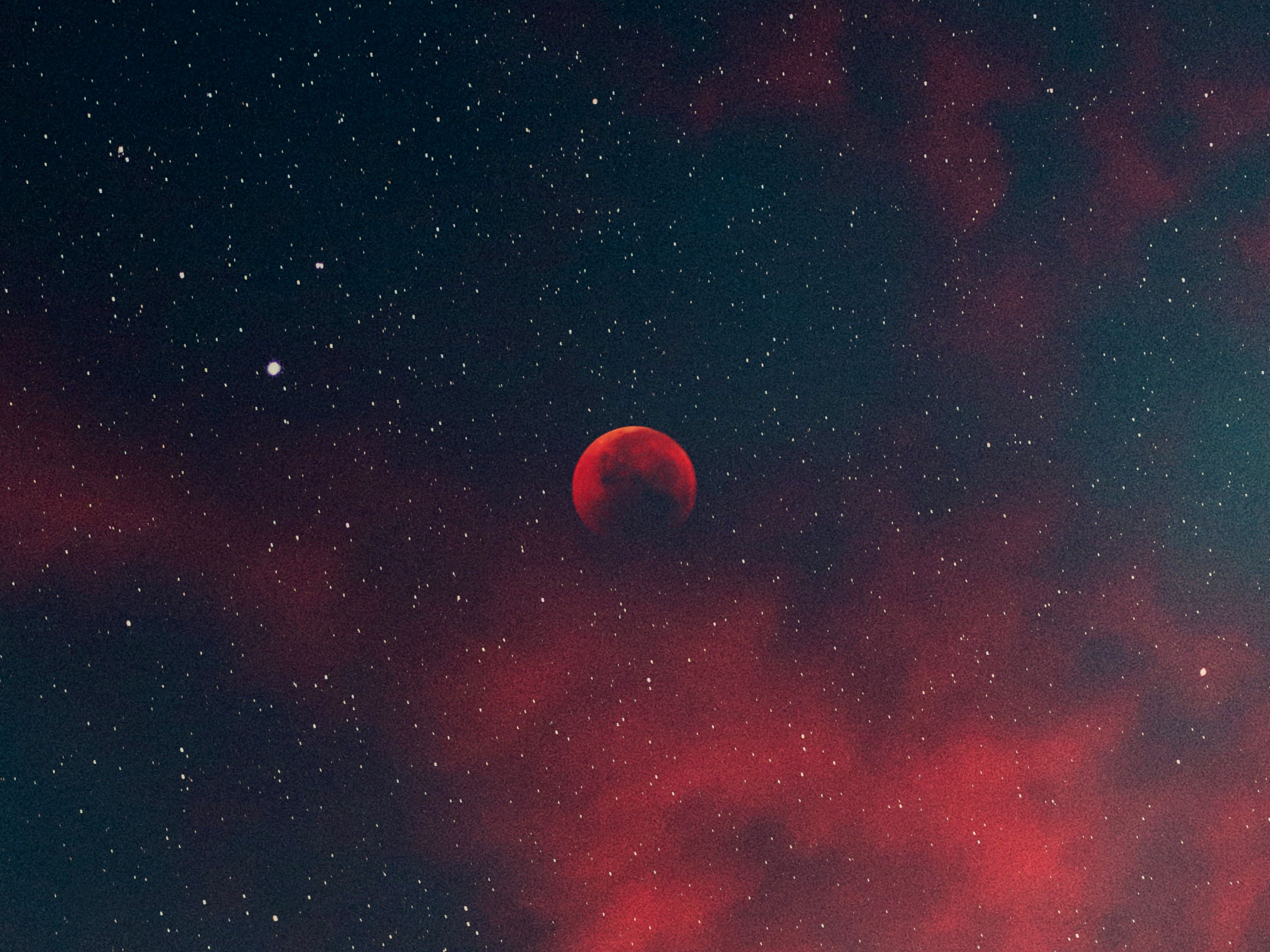 Blood moon glowing red against a deep starfield with crimson nebula clouds, representing space science and exploration
