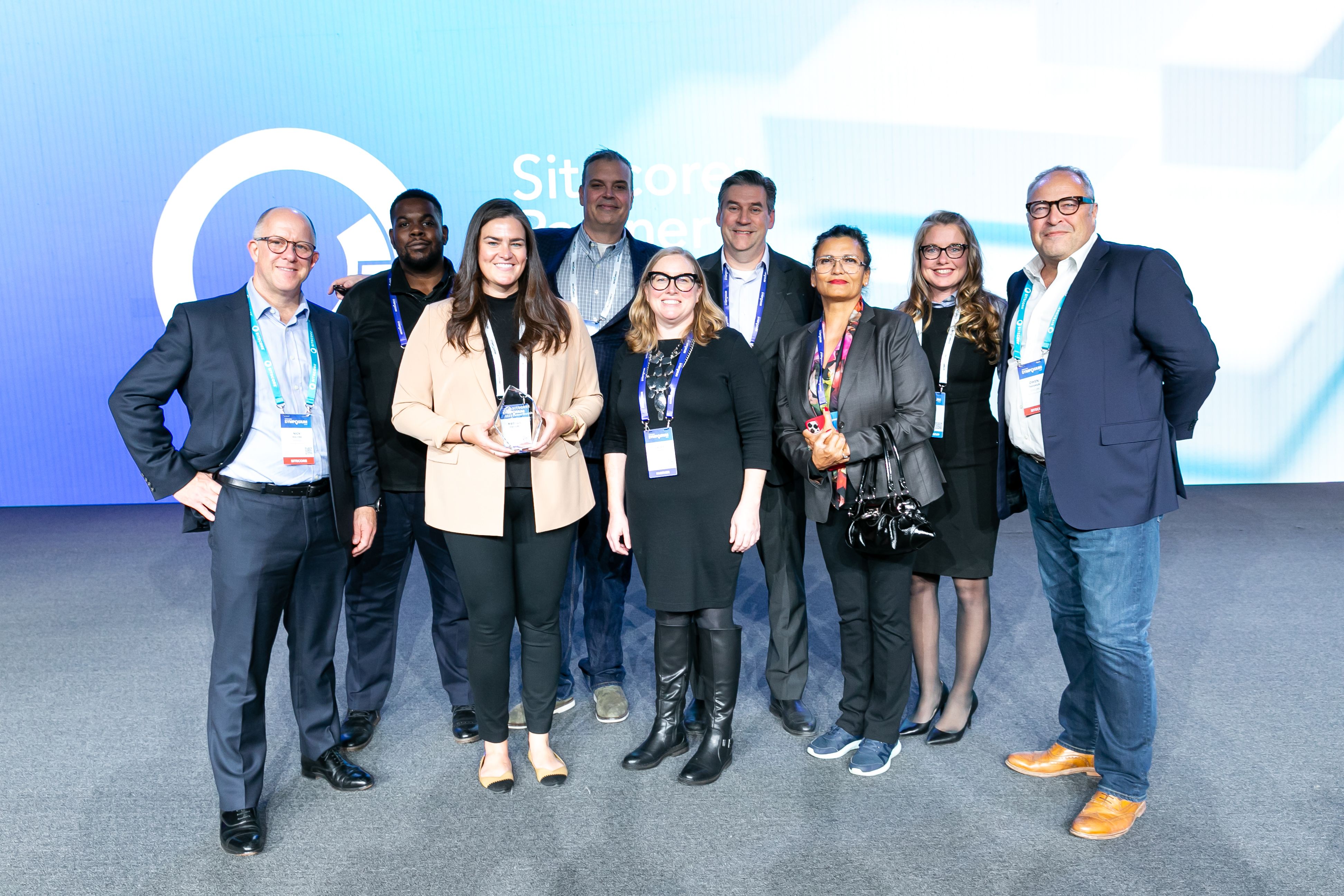 AgencyQ team members posing together on stage at a Sitecore conference with an award