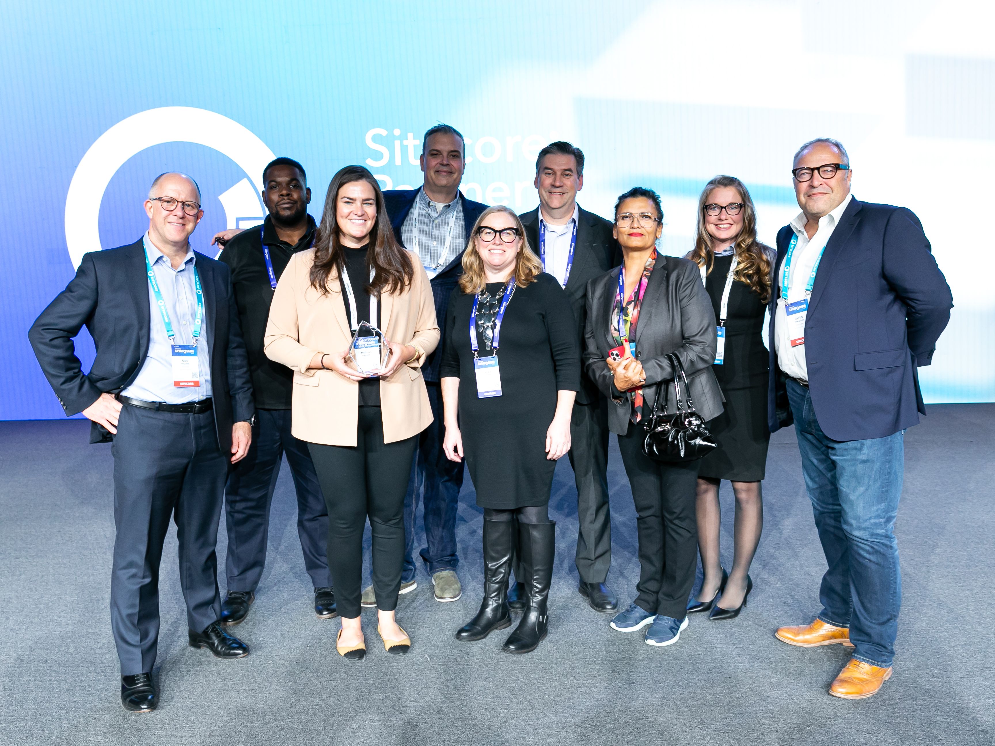 AgencyQ team members posing together on stage at a Sitecore conference with an award