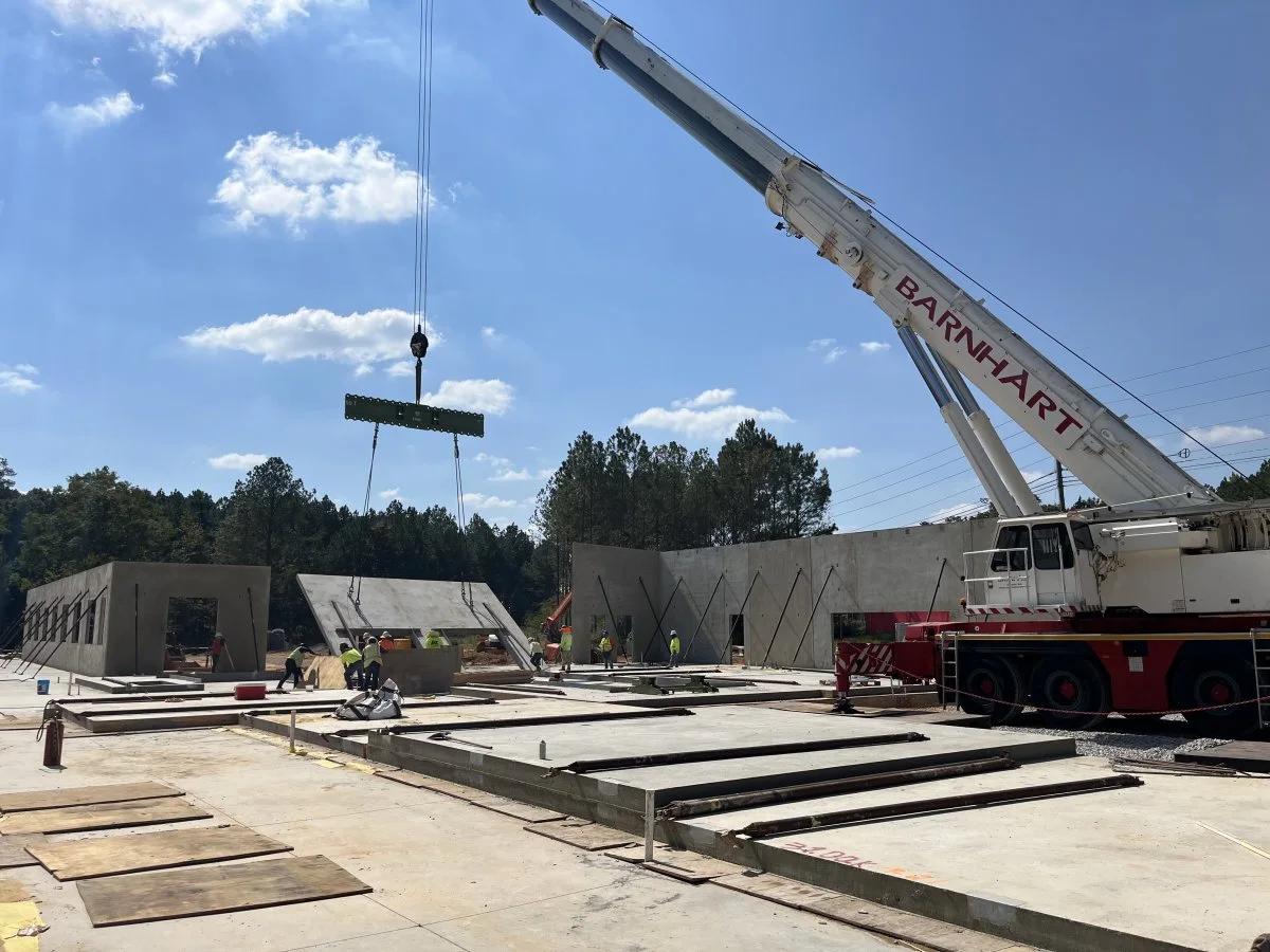 A crane raising a concrete tilt-up panel at an AIC project