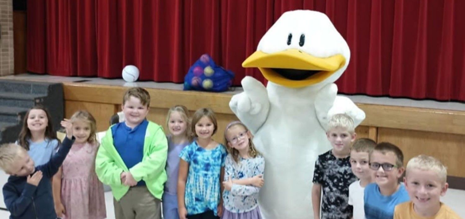 Students posing with Duck from Click, Clack, Moo in front of the stage.