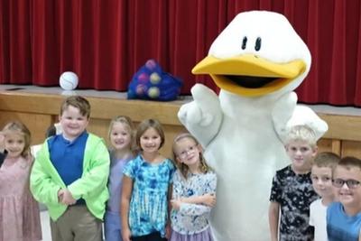Students posing with Duck from Click, Clack, Moo in front of the stage.