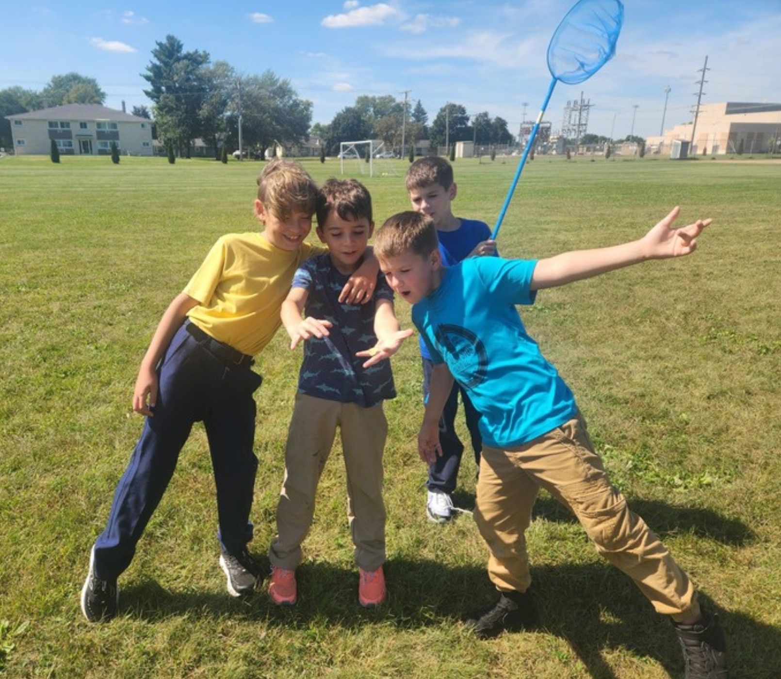 Students with a butterfly net striking a pose on the school field.