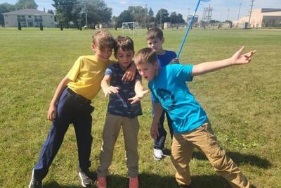 Students with a butterfly net striking a pose on the school field.
