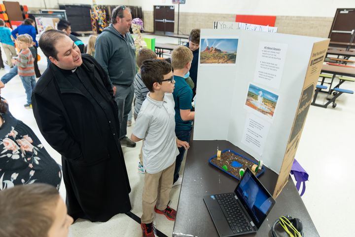 Cousins Vincent (not in photo) and Gabe Krejchik (5), explain to Fr. Cristian about how geysers work.