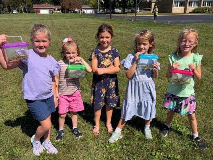 Students holding up their bug catchers on the school field.
