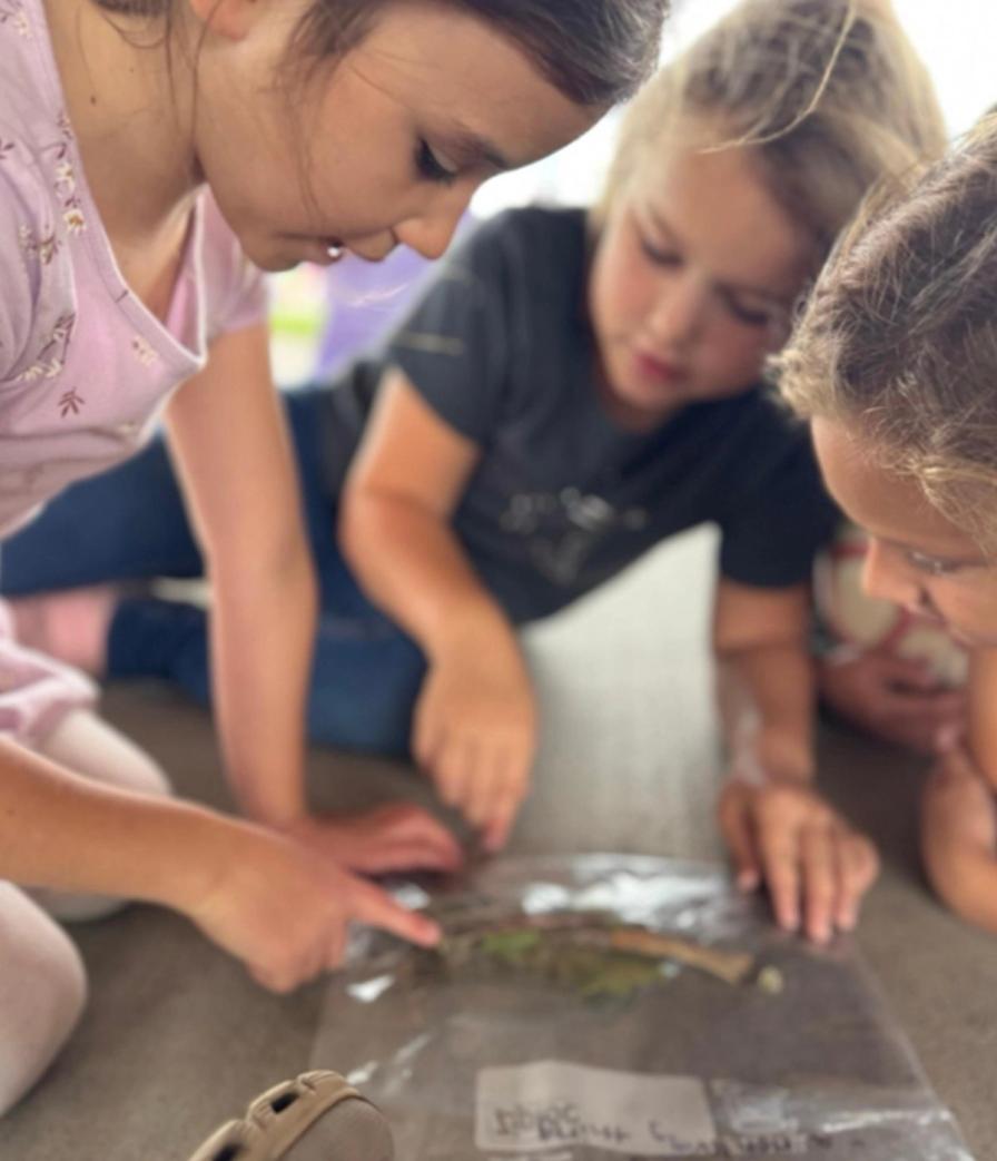 Second graders sorting their scavenger hunt finds on the ground.