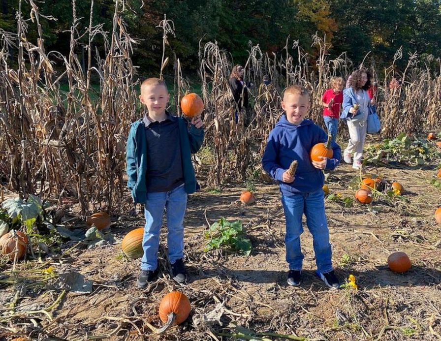 Two students holding the pumpkins they picked in the pumpkin patch.