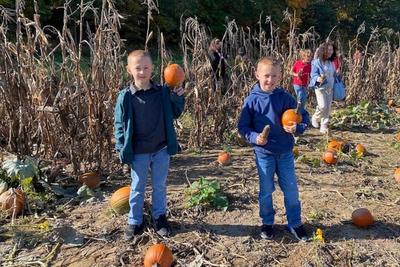 Two students holding the pumpkins they picked in the pumpkin patch.